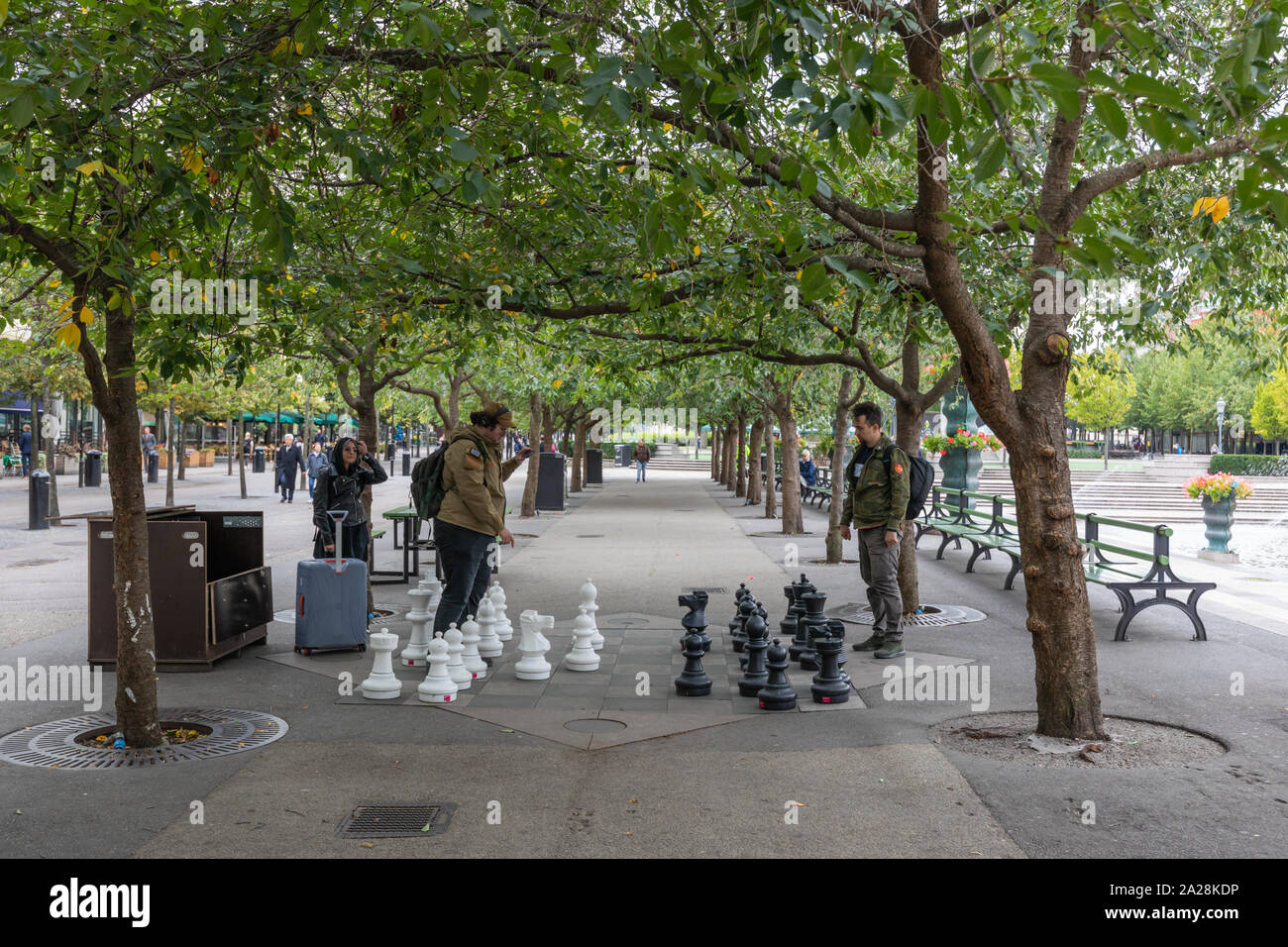 Stockholm, Suède, septembre 2019 : Deux jeunes hommes jouer aux échecs en plein air avec de grandes pièces des échecs sous des arbres dans Kungsträdgården. Banque D'Images