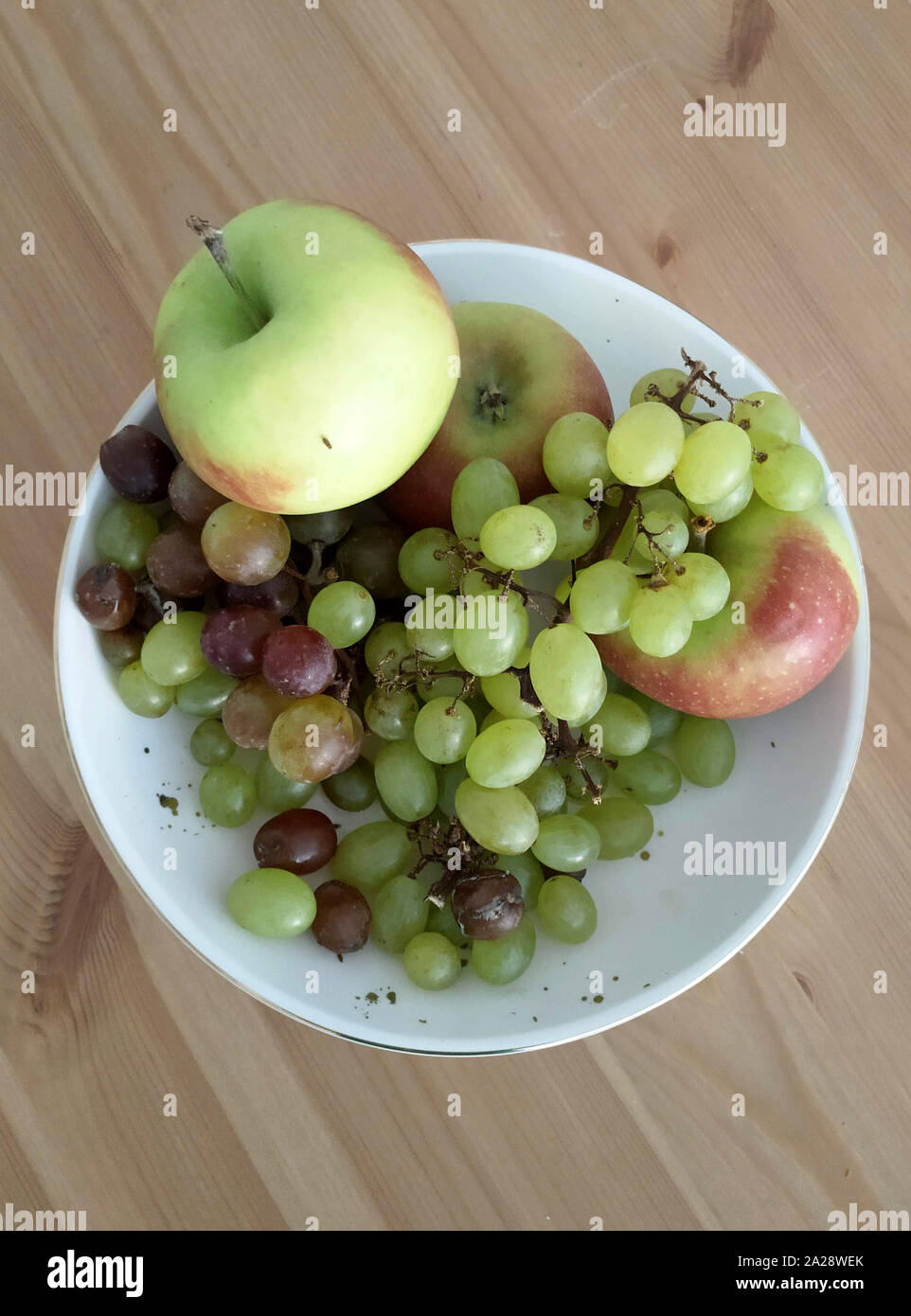 La plaque avec les pommes et raisins Banque D'Images