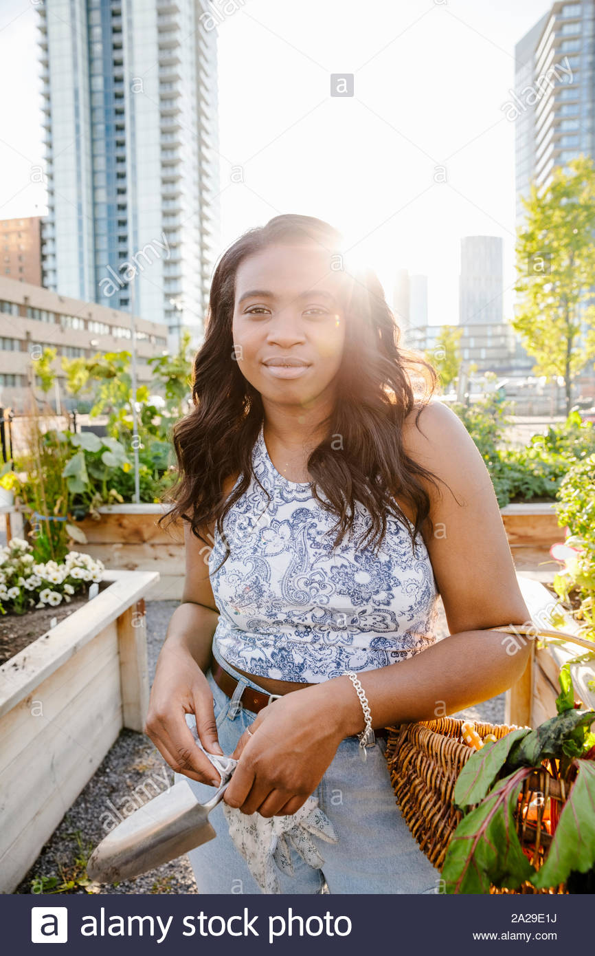 Portrait jeune femme confiante sous le soleil, le jardin de la communauté urbaine Banque D'Images