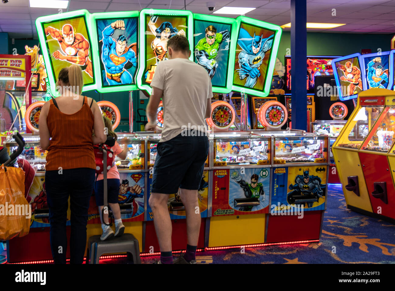 Une jeune famille de jouer les deux machines à sou ou pièce de pousser le jeu dans une salle de jeux électroniques Banque D'Images