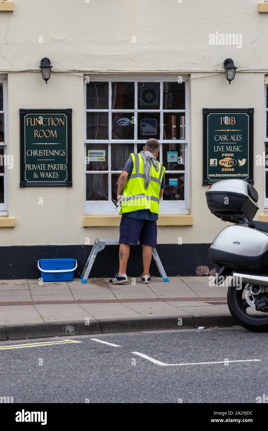 Un nettoyant pour vitres portant un gilet de nettoyer les fenêtres de pub Banque D'Images