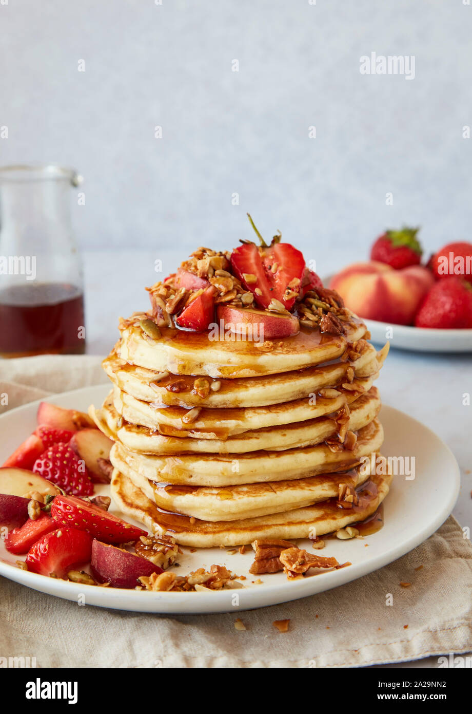 Pile de crêpes aux fraises américain, pêches, granola et sirop d'érable Banque D'Images