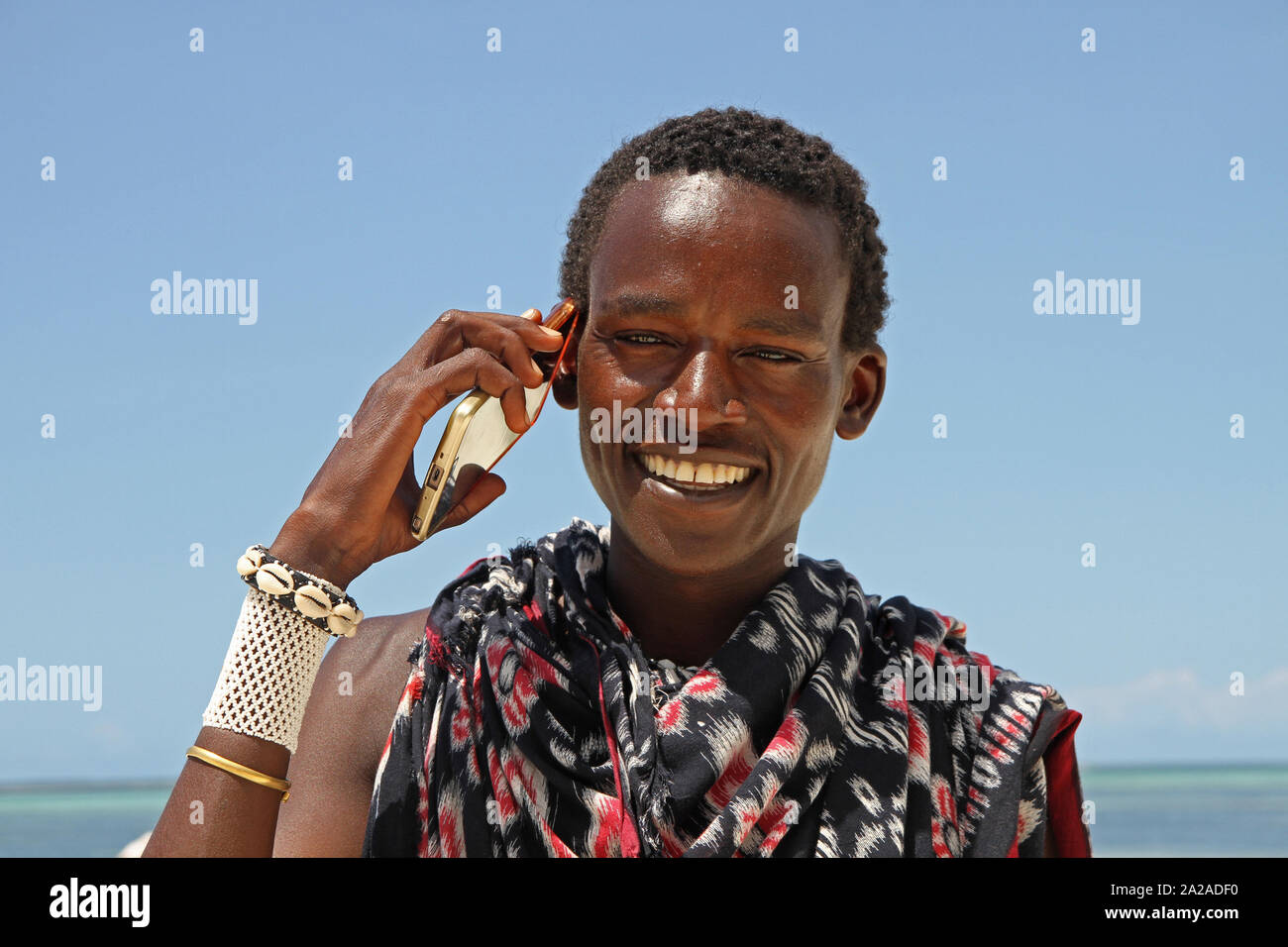 Homme massaï avec cellphone debout sur la plage, Zanzibar, l'île de Unguja, Tanzanie. Banque D'Images