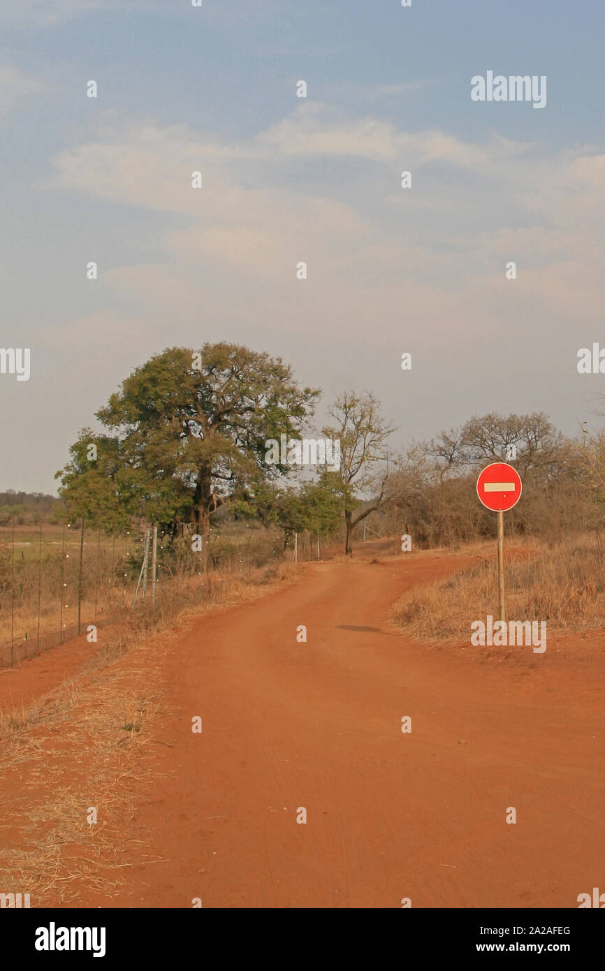 Clôture et aucun signe d'entrée sur chemin de terre dans le bushveld, Marloth Park, en bordure du Parc National Kruger. Banque D'Images