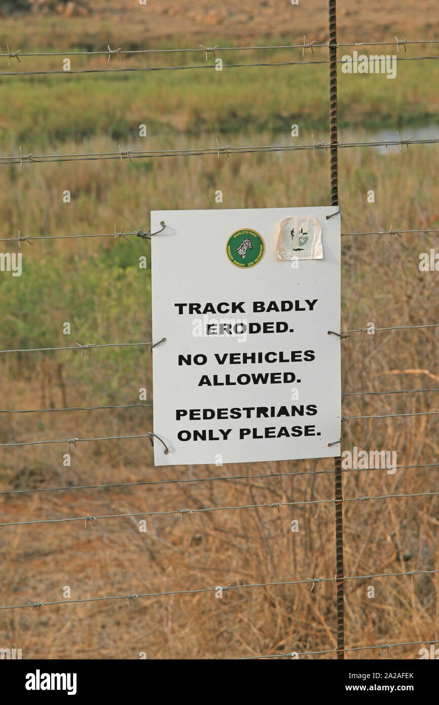 Seuls piétons signe sur clôture sur chemin de terre dans le bushveld, Marloth Park, en bordure du Parc National Kruger. Banque D'Images