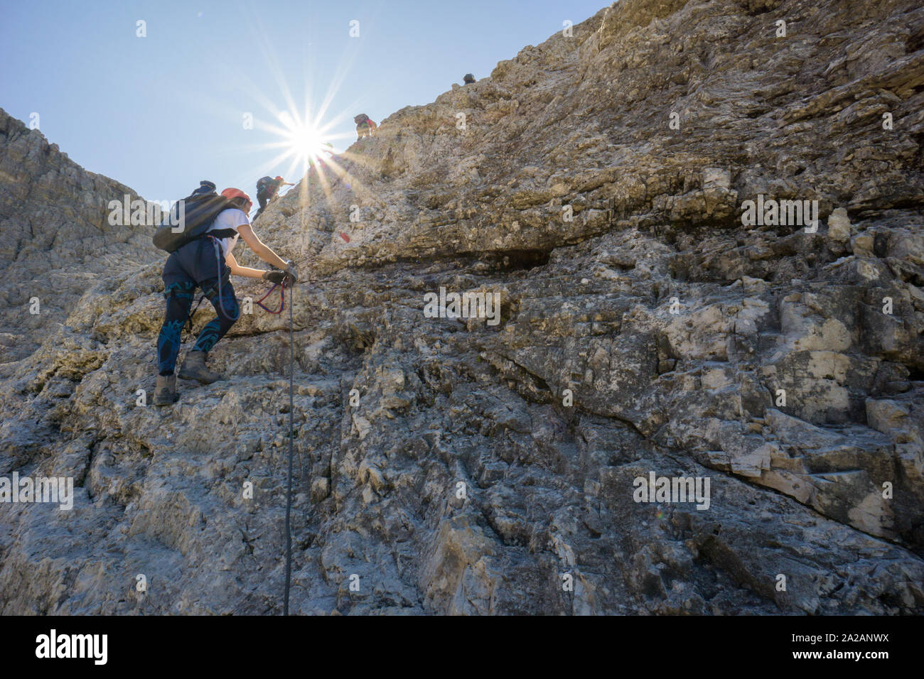 Groupe d'alpinistes sur un vertical via ferrata dans les Dolomites italiennes avec une star qui brille dans la lumière d'or Banque D'Images