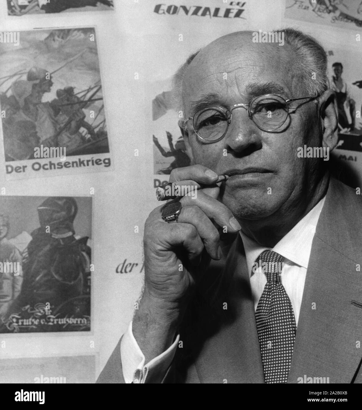 Portrait de l'pionniers du cinéma et producteur Peter Ostermayr, dans l'arrière-plan quelques affiches de ses films actuels. Ostermayr a réalisé plus de 500 films tout au long de sa vie et a été l'un des plus importants producteurs du film allemand de la première moitié du 20e siècle. Banque D'Images