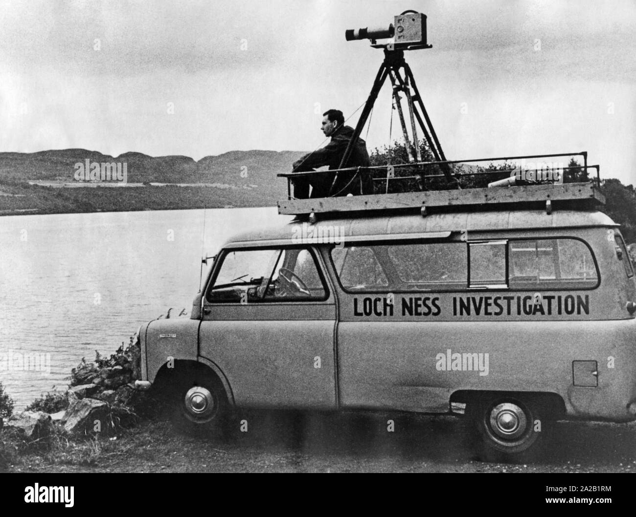 Un homme sur le toit d'un minibus avec un appareil photo attaché à lui, à la recherche au Loch Ness, dans l'espoir de voir le monstre du Loch Ness. Sur la voiture l'inscription : 'Loch Ness' enquête. Copyright : Max Scheler / SZ Photo. Banque D'Images