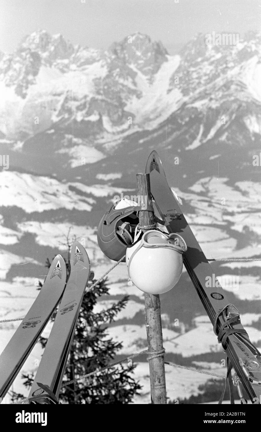 Vue d'une chaîne de montagnes des Alpes, à l'avant-plan sont les skis et casques de participants de la course du Hahnenkamm de 1962. La course du Hahnenkamm a eu lieu sur le Hahnenkamm de Kitzbühel depuis 1931. Banque D'Images