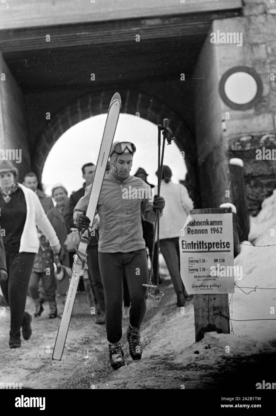 À ski Toni Sailer promenades à travers l'entrée des visiteurs de la course du Hahnenkamm avec son matériel. La course du Hahnenkamm a eu lieu sur le Hahnenkamm de Kitzbühel depuis 1931. Banque D'Images