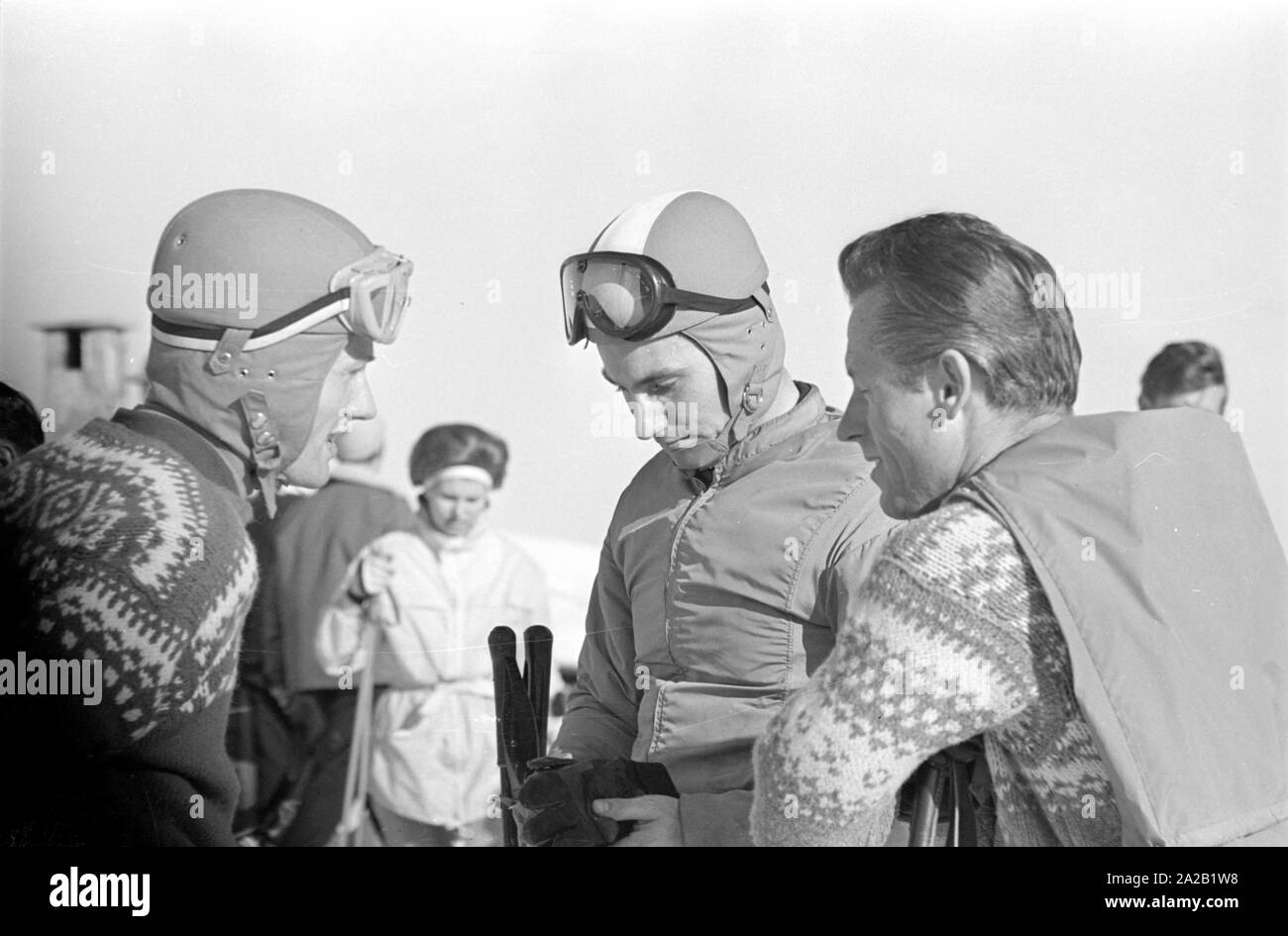 Les coureurs de ski à mettre sur le casque tout en parlant. Au milieu Toni Sailer, à droite probablement un entraîneur. Après son temps en tant qu'athlète Toni Sailer a fait carrière comme actrice, chanteuse pop et entraîneur de l'oeSV. La photo a été prise à l'occasion de la course du Hahnenkamm en 1962. La course du Hahnenkamm a eu lieu sur le Hahnenkamm de Kitzbühel depuis 1931. Banque D'Images