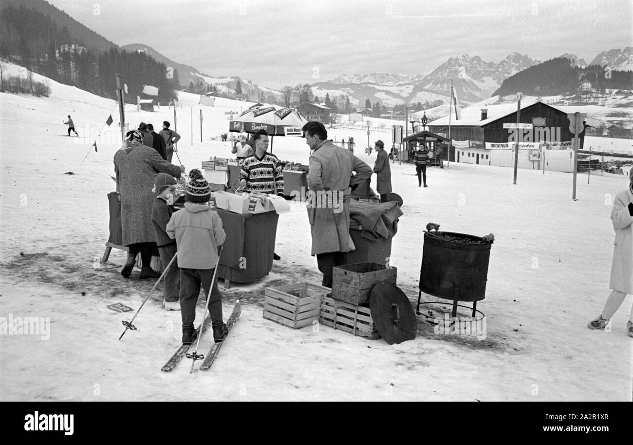 Au bord de la course du Hahnenkamm, quelques petits stands de nourriture et de boissons ont été mis en place près de la ligne d'arrivée et de l'enceinte. Ici, un stand vente de marrons chauds, en face de laquelle deux enfants sont debout. La course du Hahnenkamm a eu lieu sur le Hahnenkamm de Kitzbühel depuis 1931. Banque D'Images
