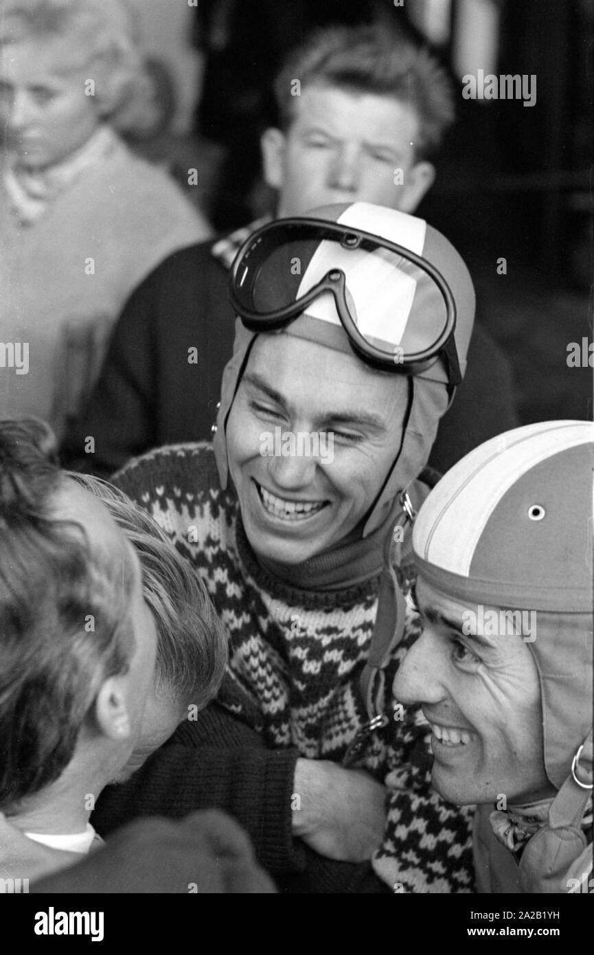Toni Sailer skieur est en train de parler à un autre participant de la course du Hahnenkamm et à certains spectateurs. La photo a probablement été prise à la gare du téléphérique à Kitzbuehel, d'où les athlètes ont fait monter la piste avec la voiture du téléphérique. La course du Hahnenkamm a eu lieu sur le Hahnenkamm de Kitzbühel depuis 1931. Banque D'Images
