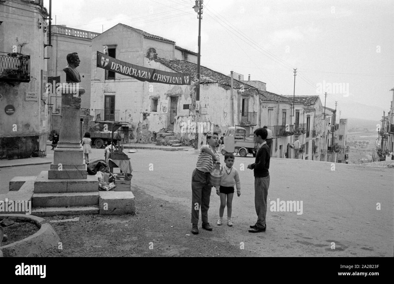 Vue d'un carré dans la petite ville de Montelepre, avec des enfants dans le centre et un monument situé sur la gauche. Dans l'arrière-plan, une publicité bannière de la partie "emocrazia Cristiana". Montelepre dans la province de Palerme (Sicile) est à 26 km seulement de la ville de Palerme. Ancien héros folklorique sicilien Salvatore Giuliano est né à Montelepre en 1922, et il est enterré dans le cimetière de l'Est (Ostfriedhof) de la ville. Les habitants de Montelepre vivent principalement de l'agriculture. Banque D'Images