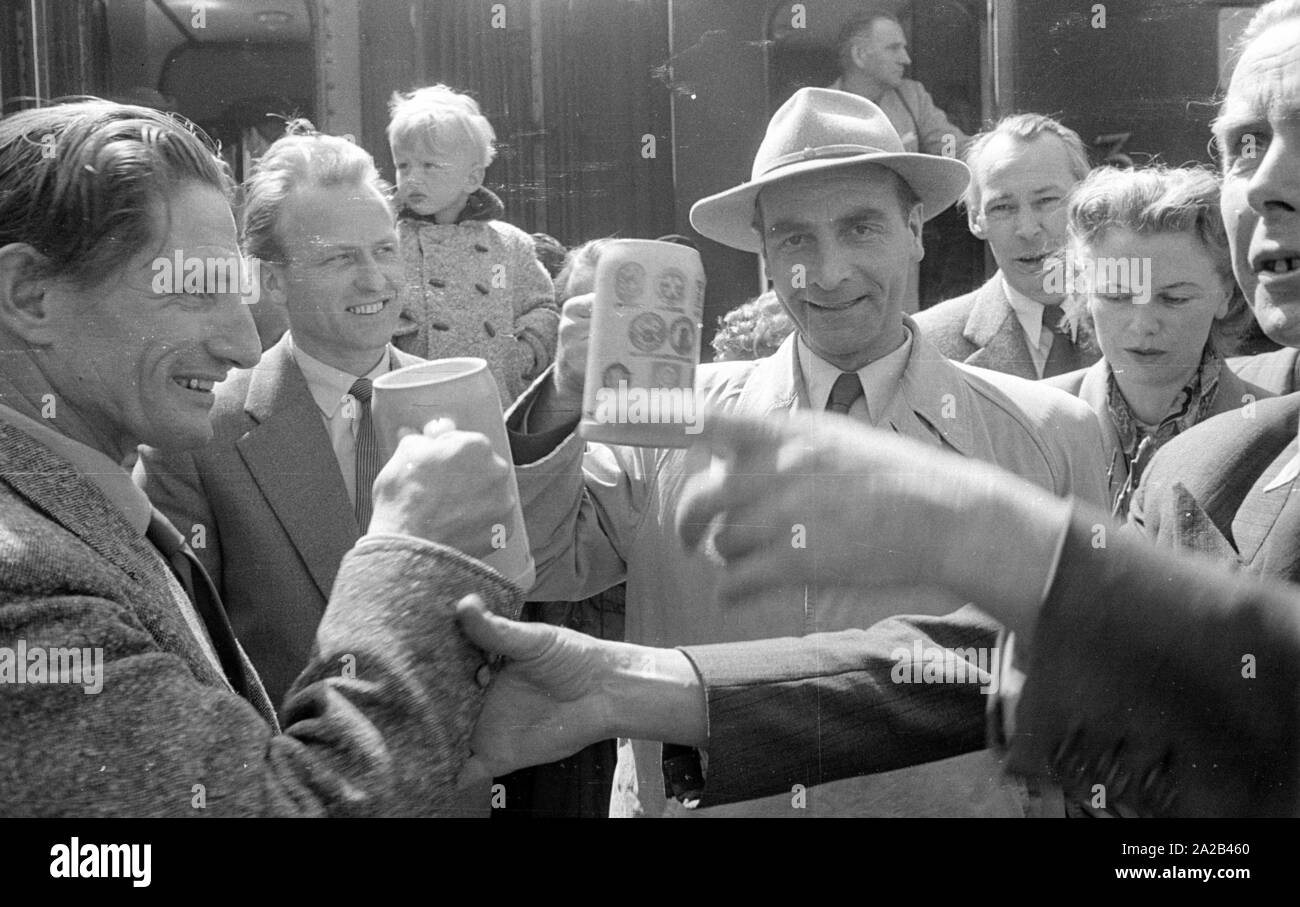La photo montre probablement membres de l'expédition dans l'Himalaya à la large pic entre août et décembre 1954. Le voyage pour la région himalayenne explique le jour de départ le 28 avril. Les alpinistes participantes disent au revoir à leurs proches et les parties intéressées à la gare principale de Munich. Les participants ont vite boire une dernière bière bavaroise. Banque D'Images