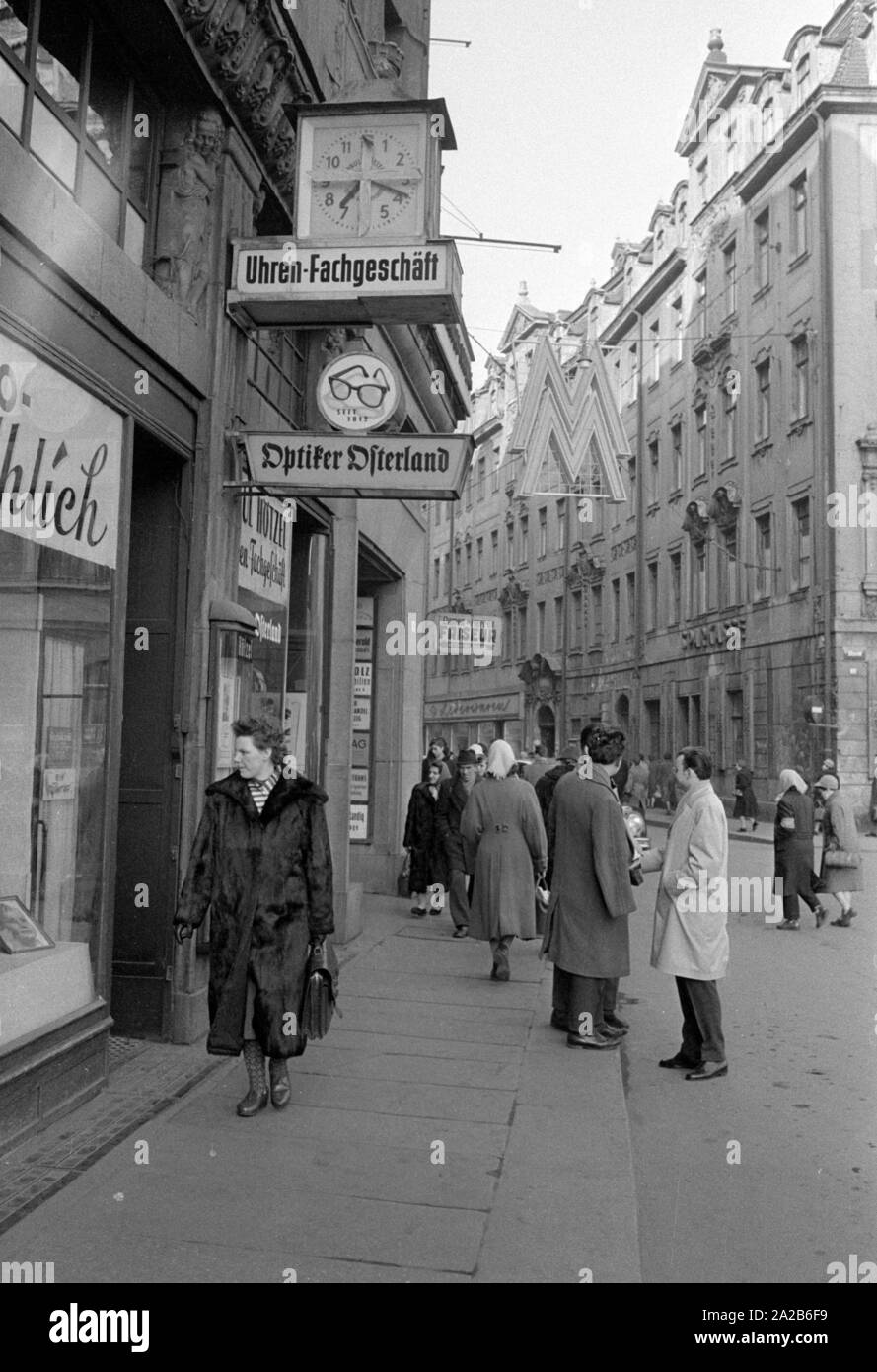 Scène de rue à Leipzig lors de la foire de printemps 1960. Au-dessus du trottoir le logo de la foire (double M). Banque D'Images