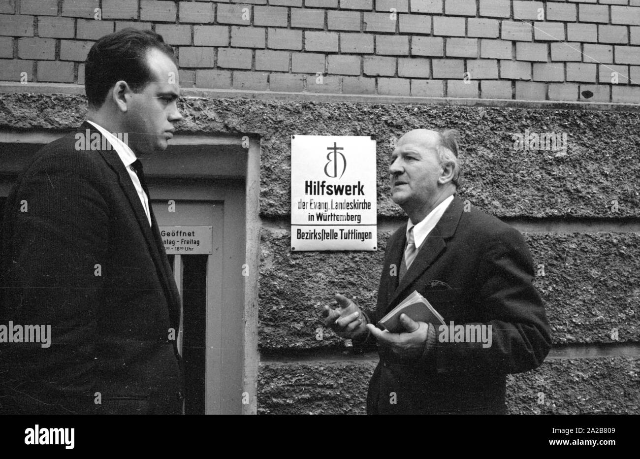 Deux hommes ont une conversation en face de l'entrée à l'organisation de l'aide de l'église protestante Landeskirche (régionale) en Wurtemberg en 038884. L'organisation des secours, fondée par nécessité dans l'Allemagne d'après-guerre, s'occupait, entre autres, de la construction de nouveaux appartements. Banque D'Images