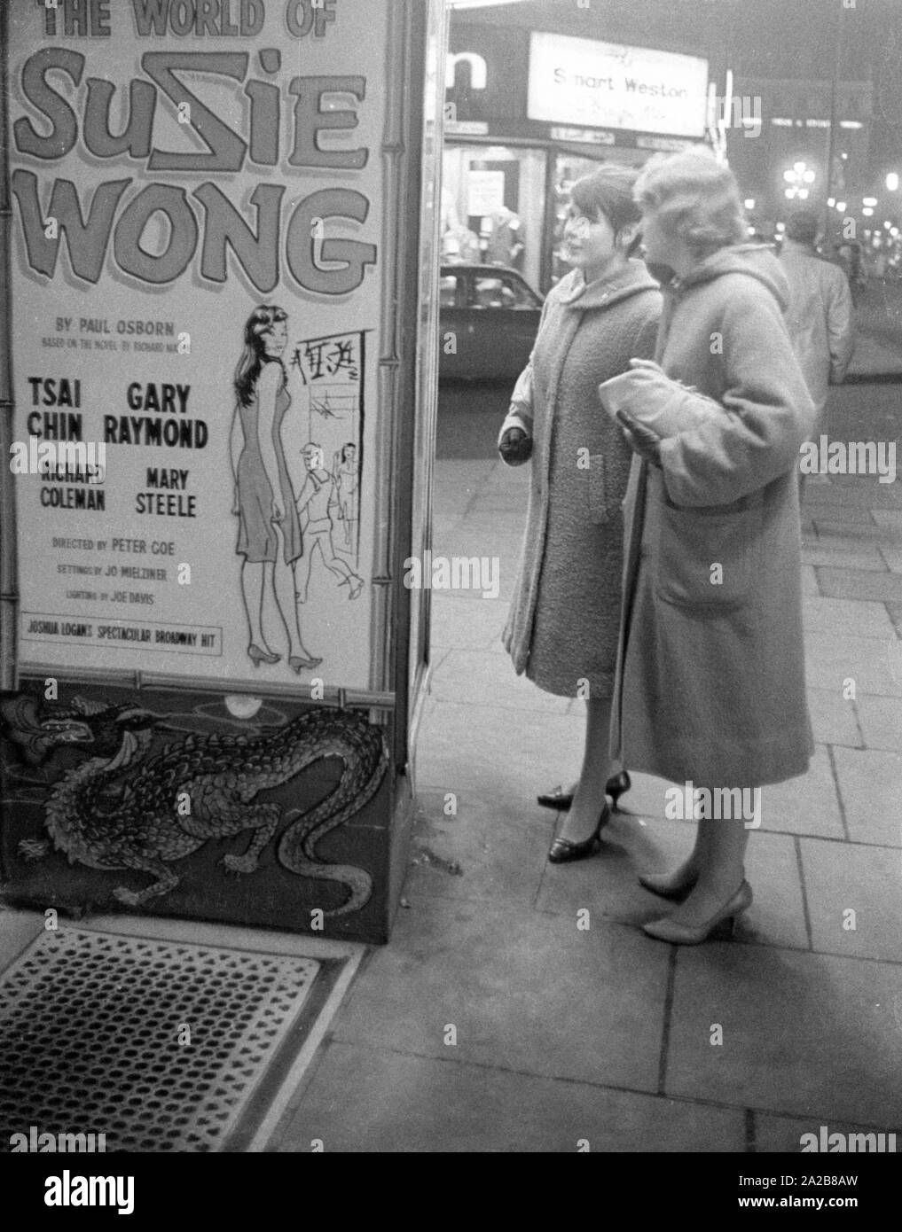 Deux femmes regardez une publicité pour le film "Le Monde de Suzie Wong" près de Piccadilly à Londres. Banque D'Images