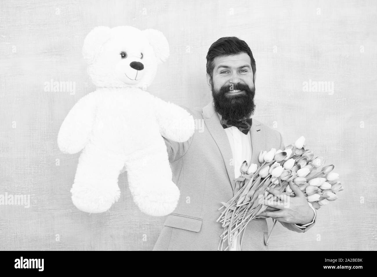 Surprise pour elle. Gentleman faire surprise romantique pour elle. Monsieur cadeau romantique. Voeux d'anniversaire. Joyeux anniversaire mon amour. Costume homme barbu homme noeud papillon maintenez l'ours en peluche et bouquet. Banque D'Images