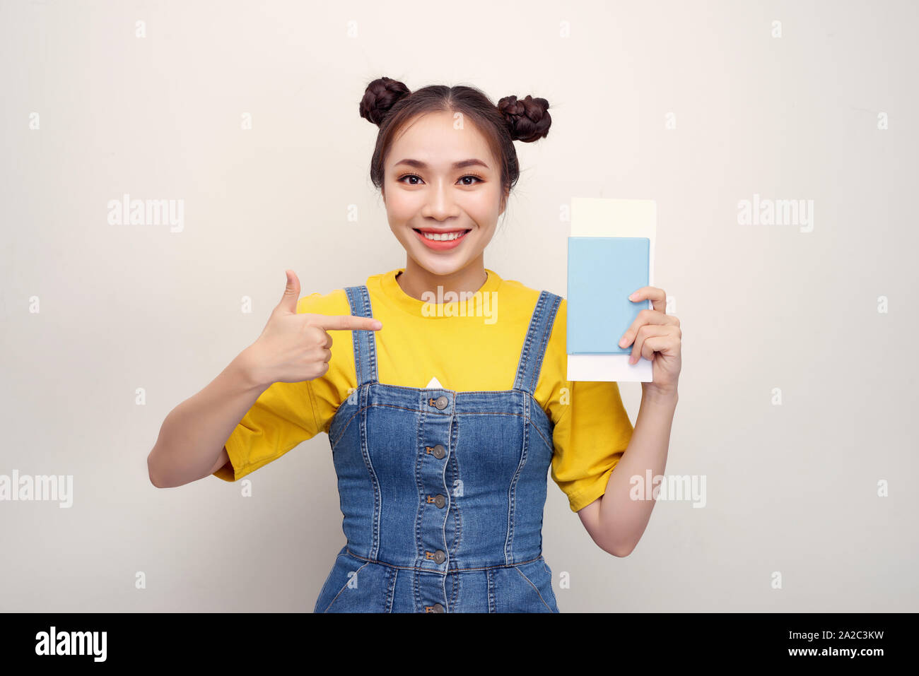 Jolie femme excité 20s smiling while holding passport avec billets de voyage isolé sur fond blanc Banque D'Images