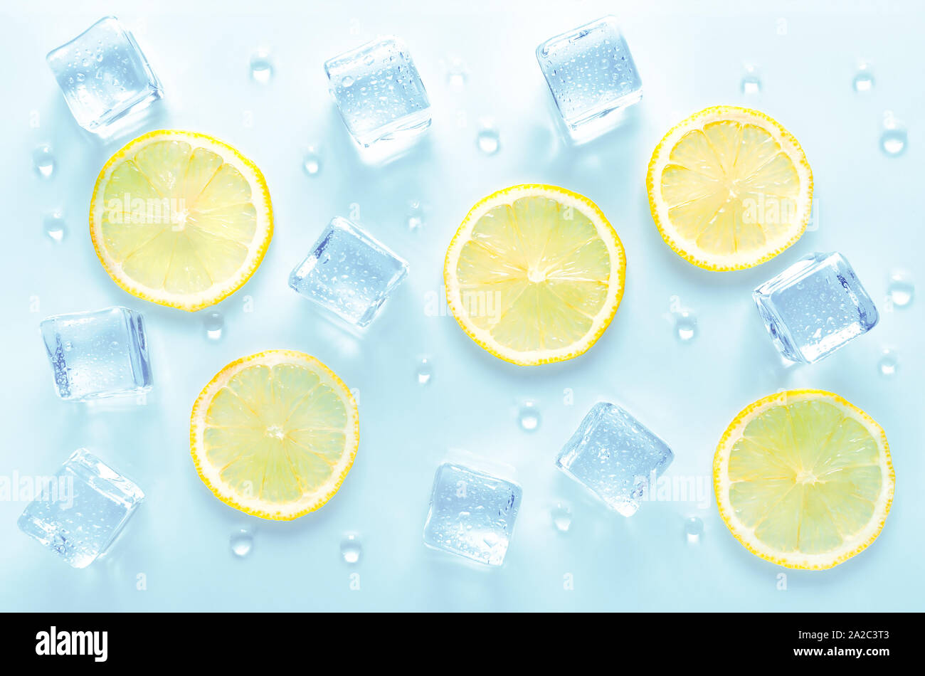 Des cubes de glace et de tranche de citron frais avec des gouttes d'eau sur fond bleu Banque D'Images