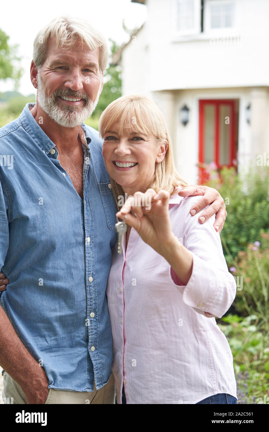 Portrait Of Mature Couple debout dans un jardin en face de maison de rêve en campagne Holding Keys Banque D'Images