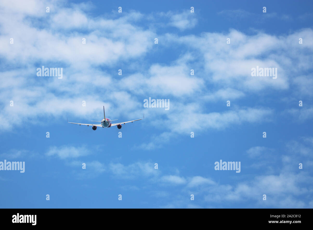 Vol d'un avion dans le ciel bleu sur fond de nuages blancs, vue arrière. Moteur deux-avion commercial pendant le virage, la turbulence et le concept de voyage Banque D'Images