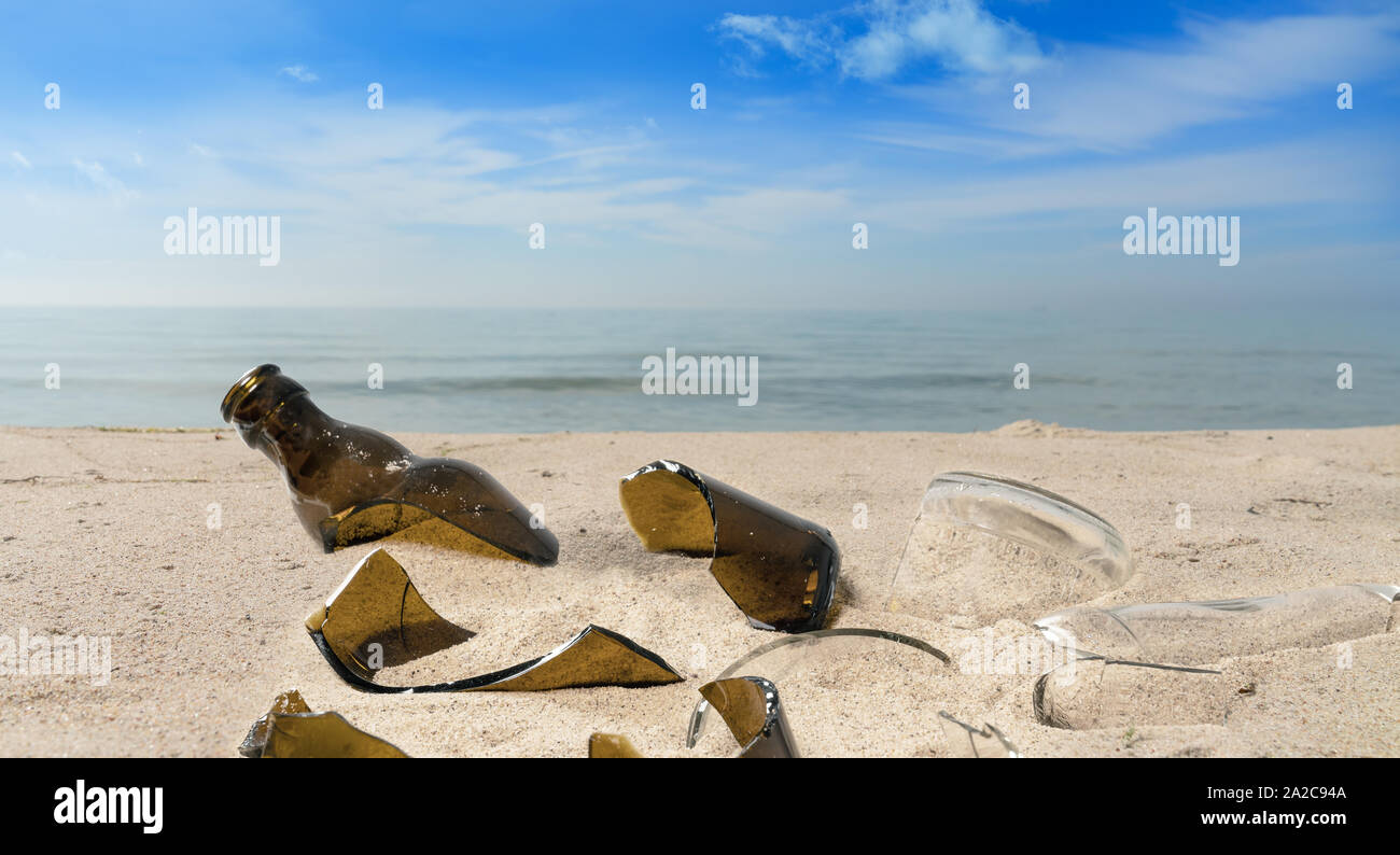 La pollution par les bouteilles en verre brisé gisant sur une plage dans le sable Banque D'Images