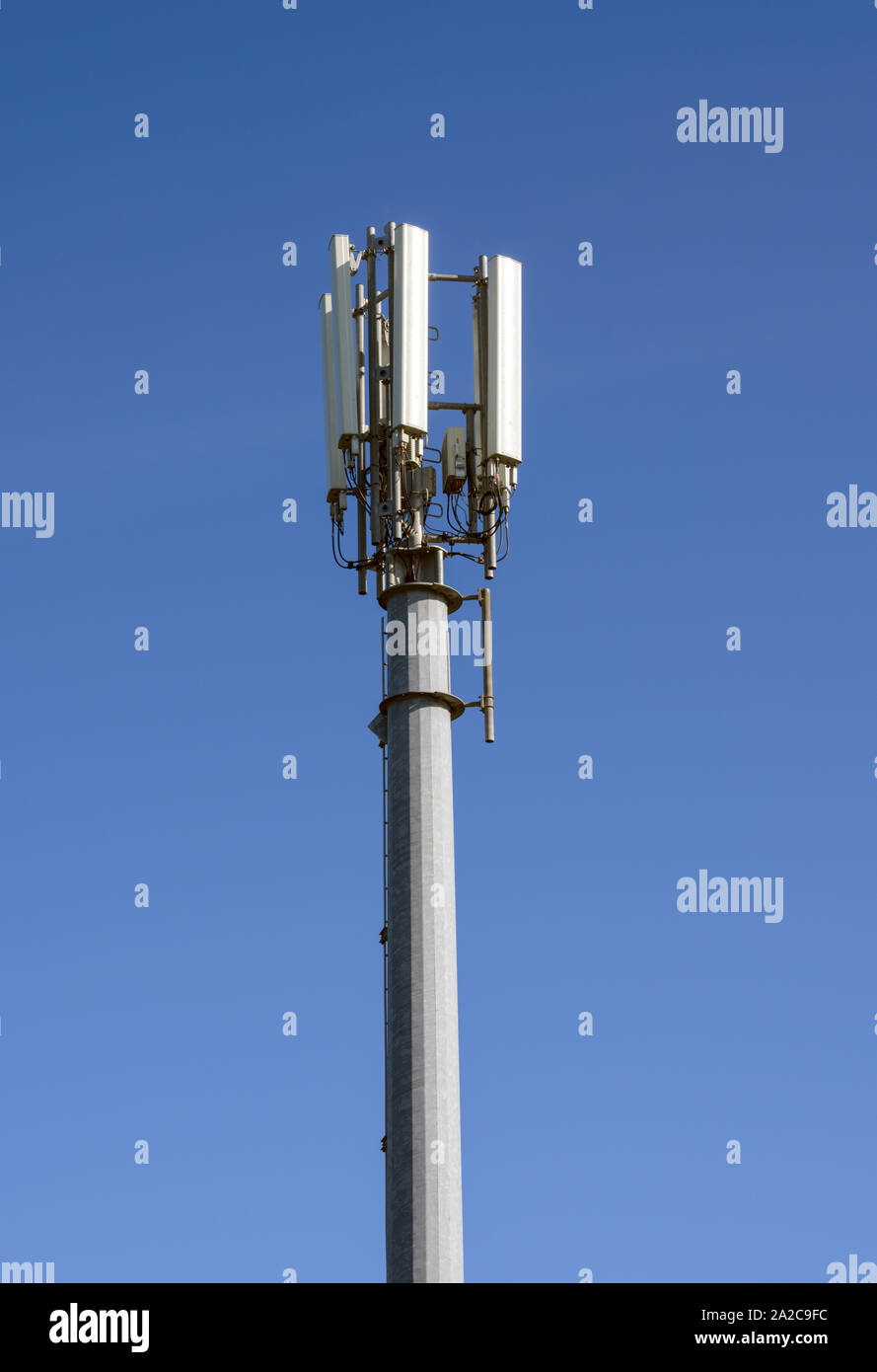 Téléphone mobile et des communications mast photographié contre un ciel bleu Banque D'Images