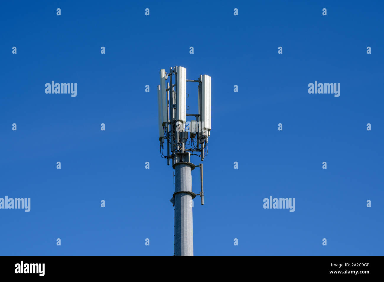 Téléphone mobile et des communications mast photographié contre un ciel bleu Banque D'Images