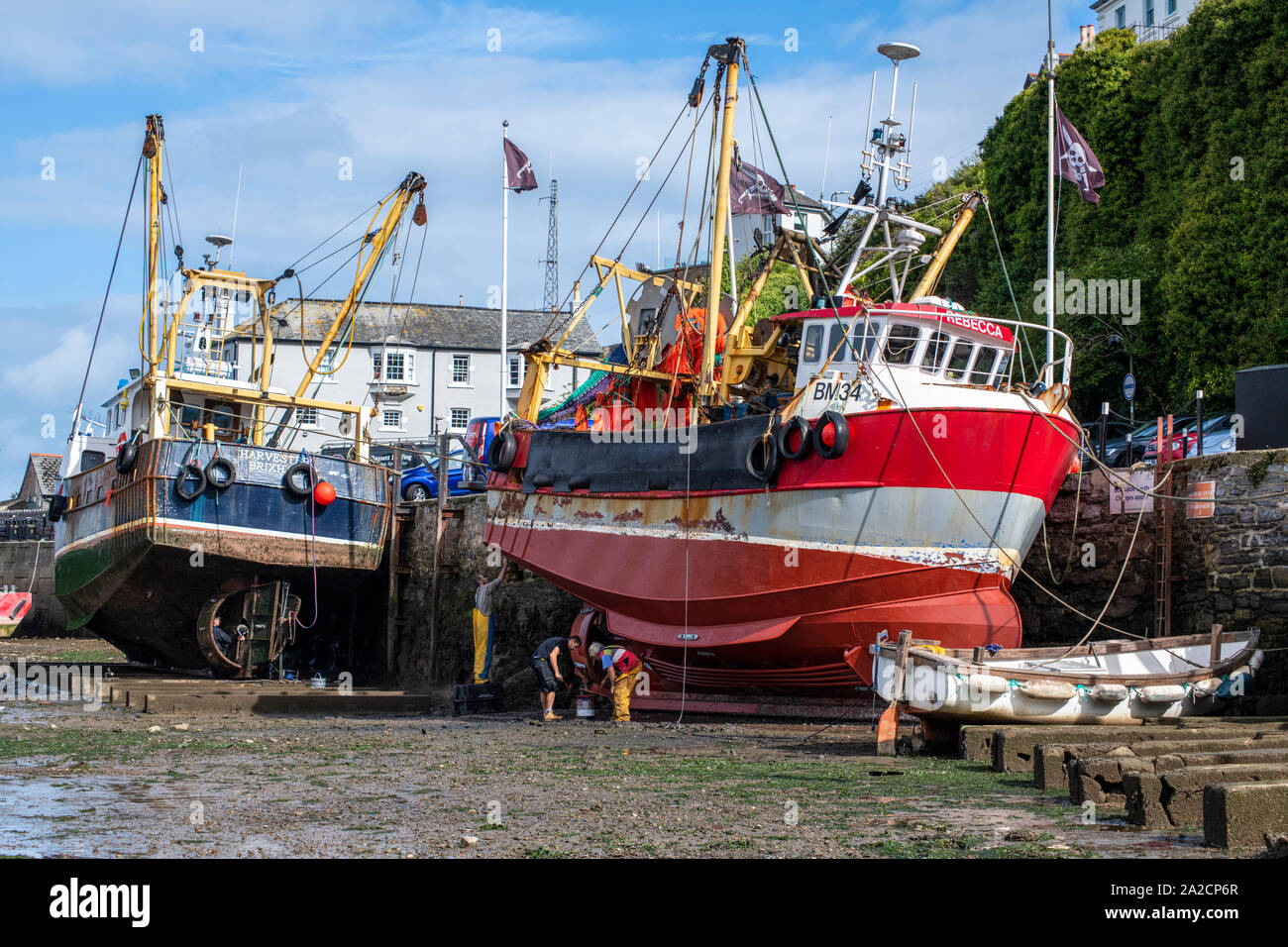 Marée basse à Brixham Harbour permet à l'occasion d'un peu d'entretien à faire sur les coques d'un couple de chalutiers à perche amarrée le long du quai Banque D'Images