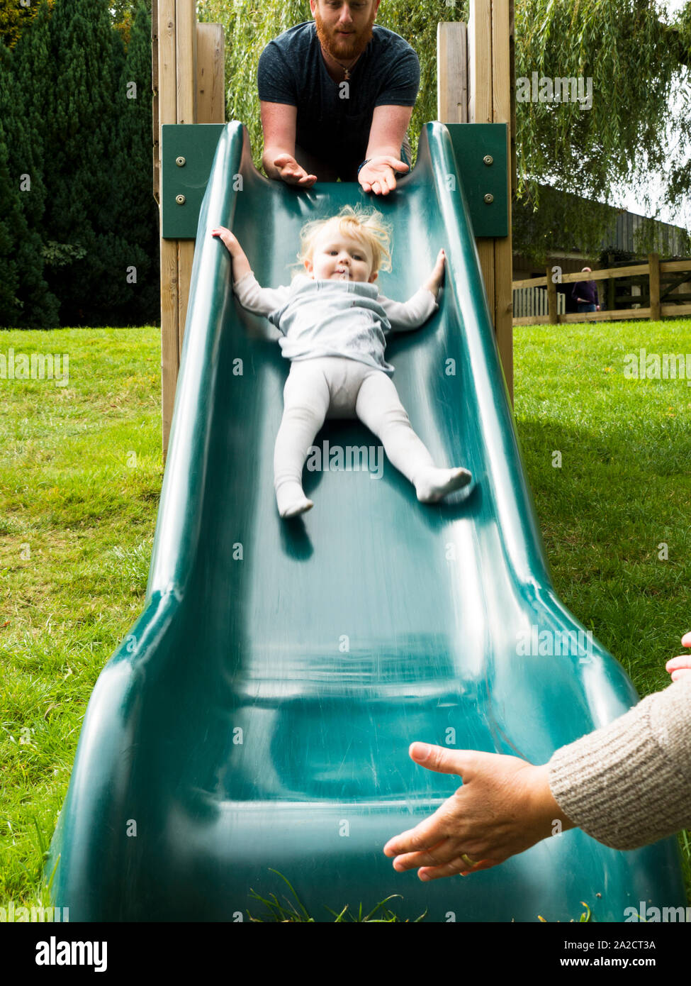 Les parents à jouer avec tout-petit sur une diapositive, UK Banque D'Images