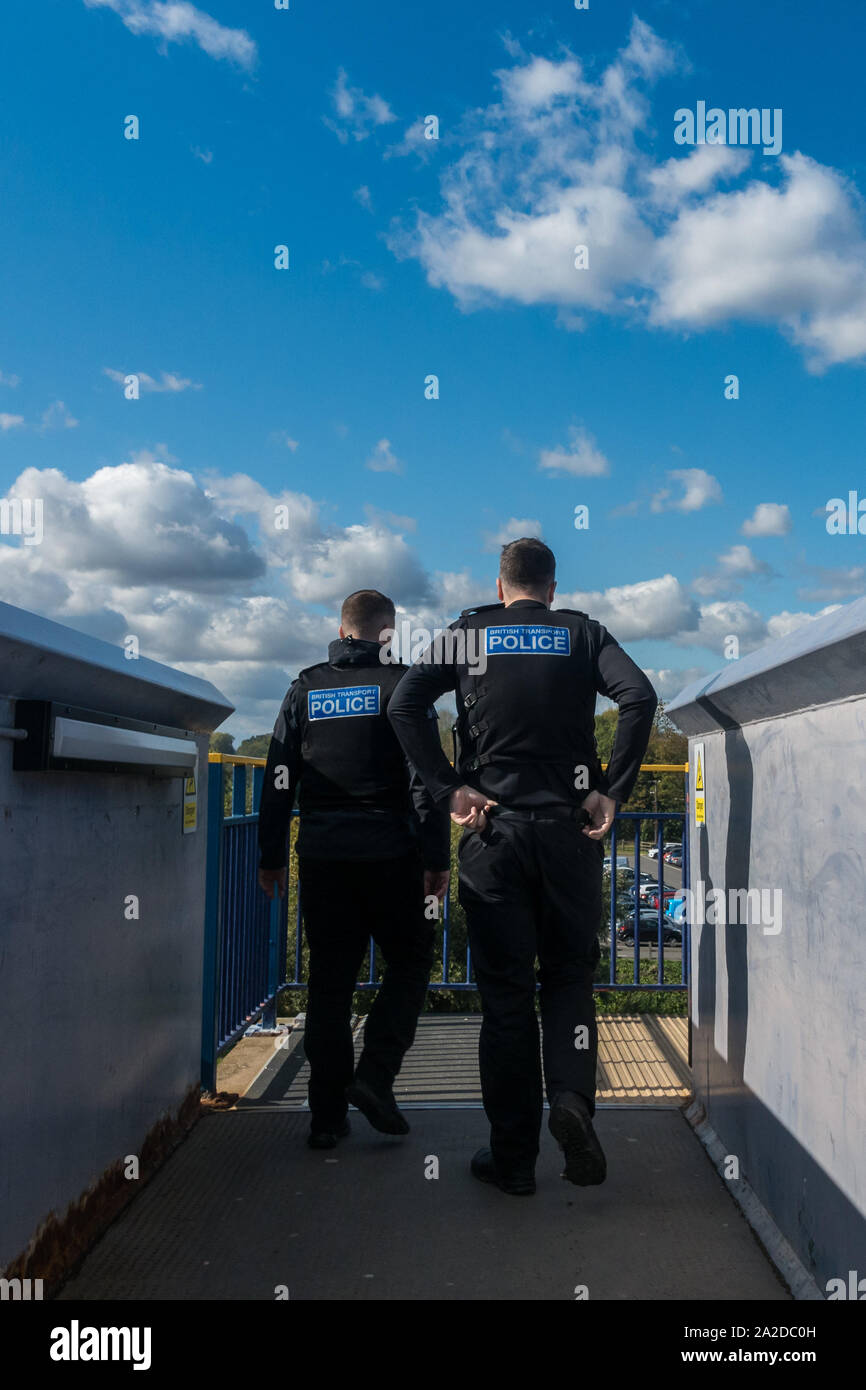 Deux agents de la police britannique des Transports d'hommes en uniforme de la fonction passerelle de franchissement de l'arrière. Vue arrière deux hommes ensoleillé avec ciel bleu Banque D'Images