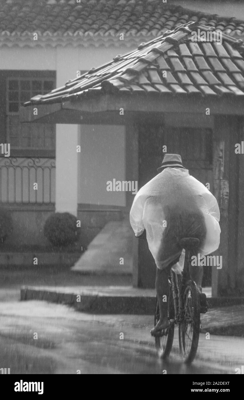 Homme randonnée à vélo sous la pluie à Tiradentes, une ville coloniale du Brésil Banque D'Images