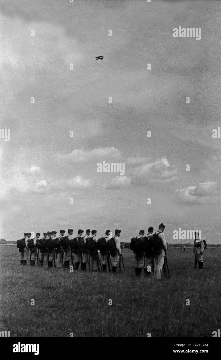 Ein Doppeldecker kreist über der Geländeübung der Rekruten der Flieger Ausbildungsstelle Schönwalde, Deutschland, 1930er Jahre. Un biplan vol au-dessus de l'exercice sur le terrain des recrues, l'Allemagne des années 1930. Banque D'Images