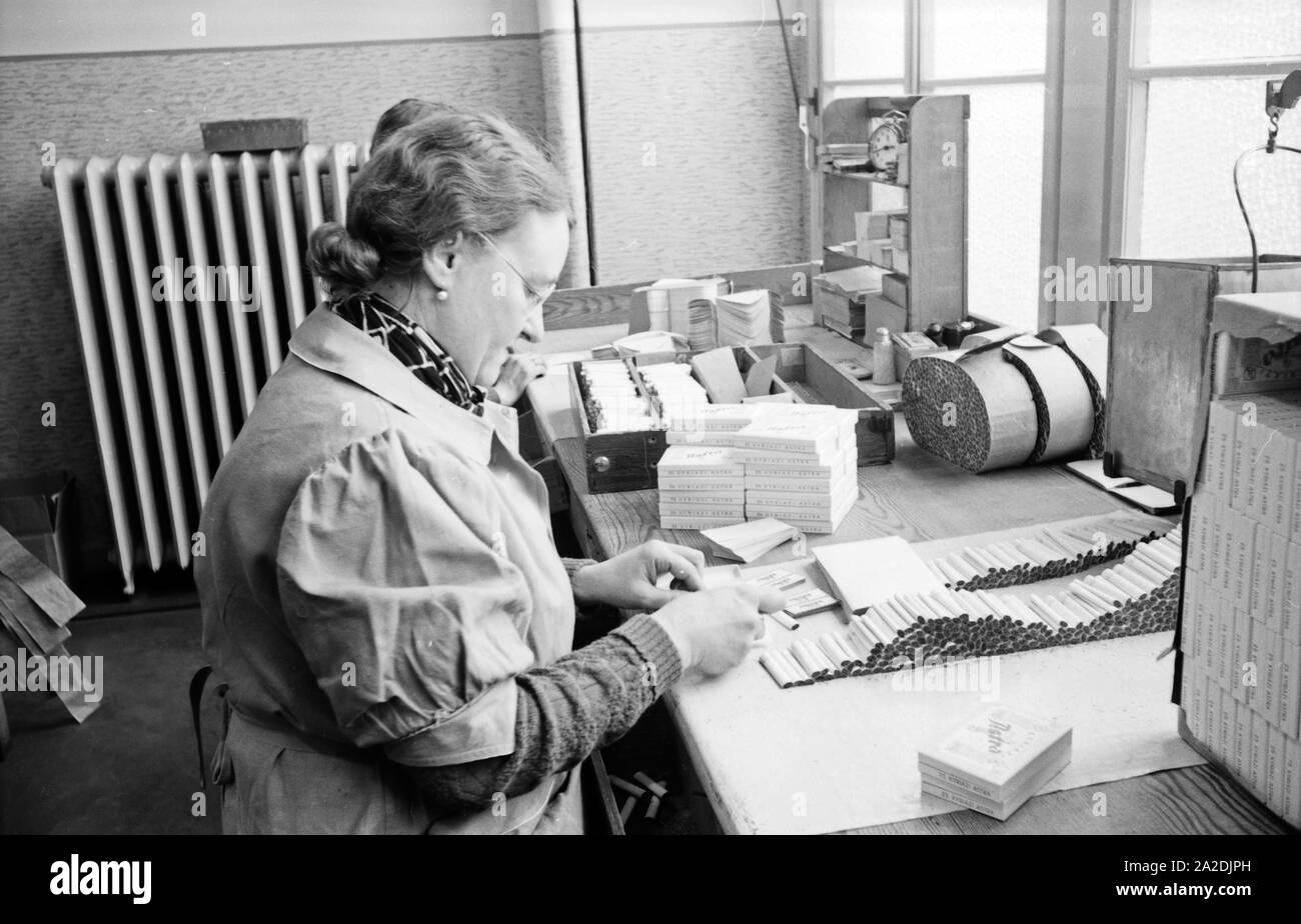 Eine/packt fertig produzierte der Zigaretten Zigarettenmarke Zigarettenschachteln dans Astra dans der Zigarettenfabrik Kyriazi dans Hamburg, Deutschland 1930 er Jahre. Membre du personnel de sexe féminin l'emballage les paquets de cigarettes à l'usine de cigarettes Kyriazi à Hambourg, Allemagne 1930. Banque D'Images