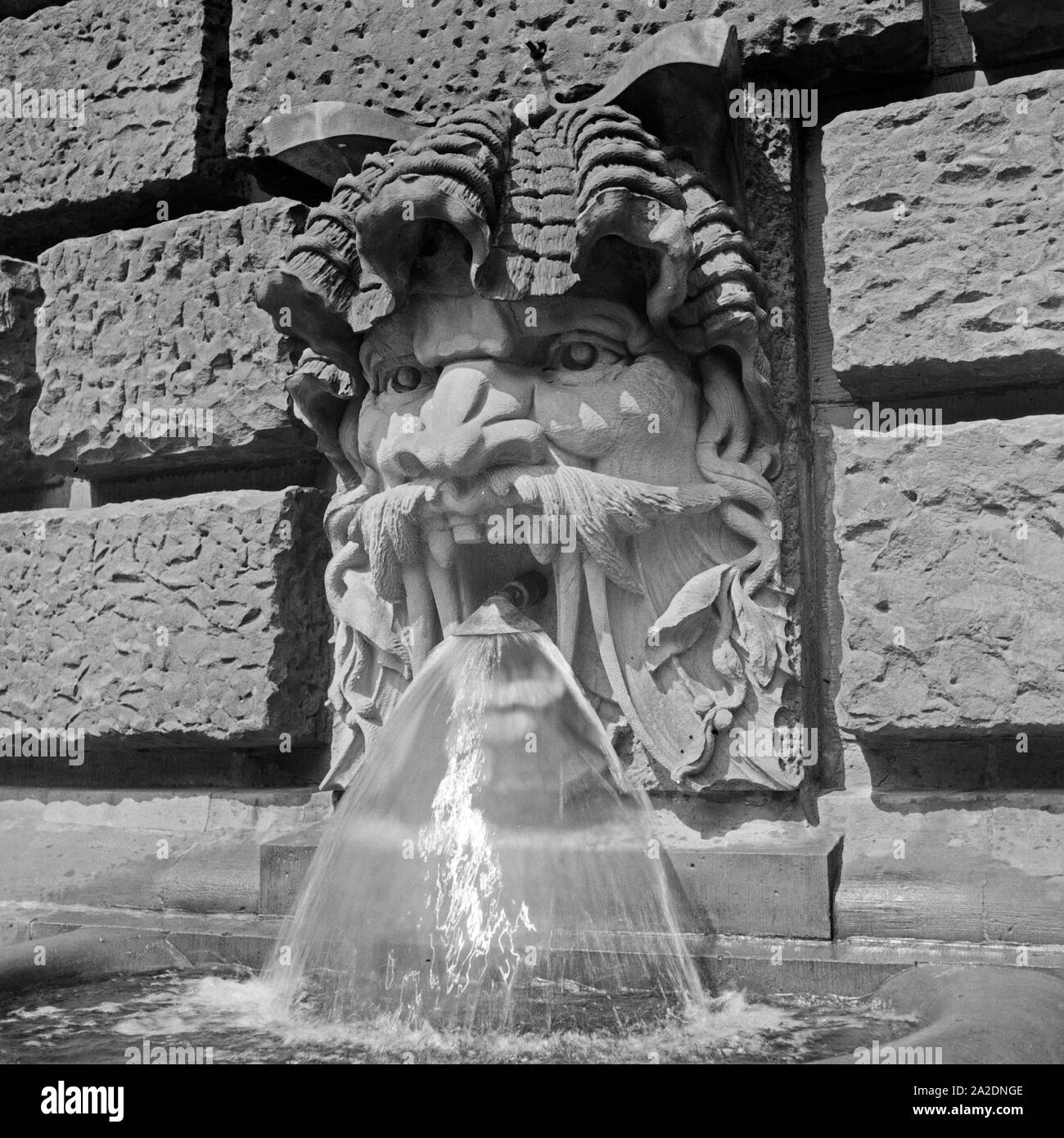 Wasserspeier speist ein einen Brunnen dans Gebäudewand von Deutschland, 1930er Jahre. Un spenidng gargouille de l'eau pour un printemps, Allemagne 1930. Banque D'Images