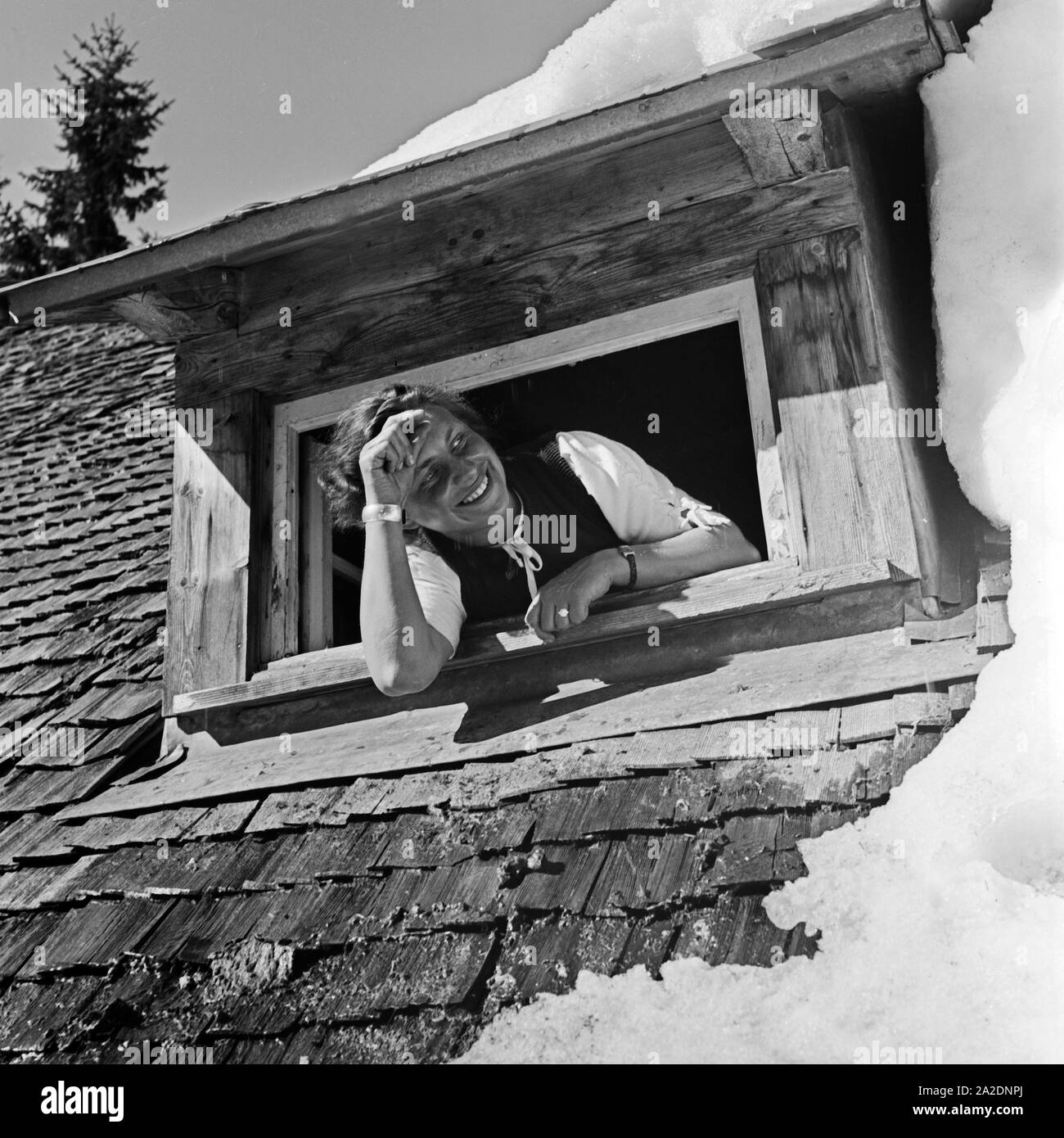 Eine junge Frau schaut aus einem verschneiten Dachfenster, Deutschland 1930 er Jahre. Une jeune femme à une fenêtre de toit dans la neige, l'Allemagne des années 1930. Banque D'Images