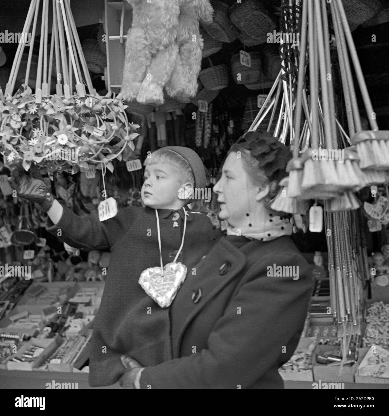 Ein kleiner Junge auf dem am Spielzeugstand bras senneur Mutter auf dem Weihnachtsmarkt Deutschland, 1930er Jahre. Un petit garçon dans les bras de sa mère au stand de jouets du marché de Noël, de l'Allemagne des années 1930. Banque D'Images