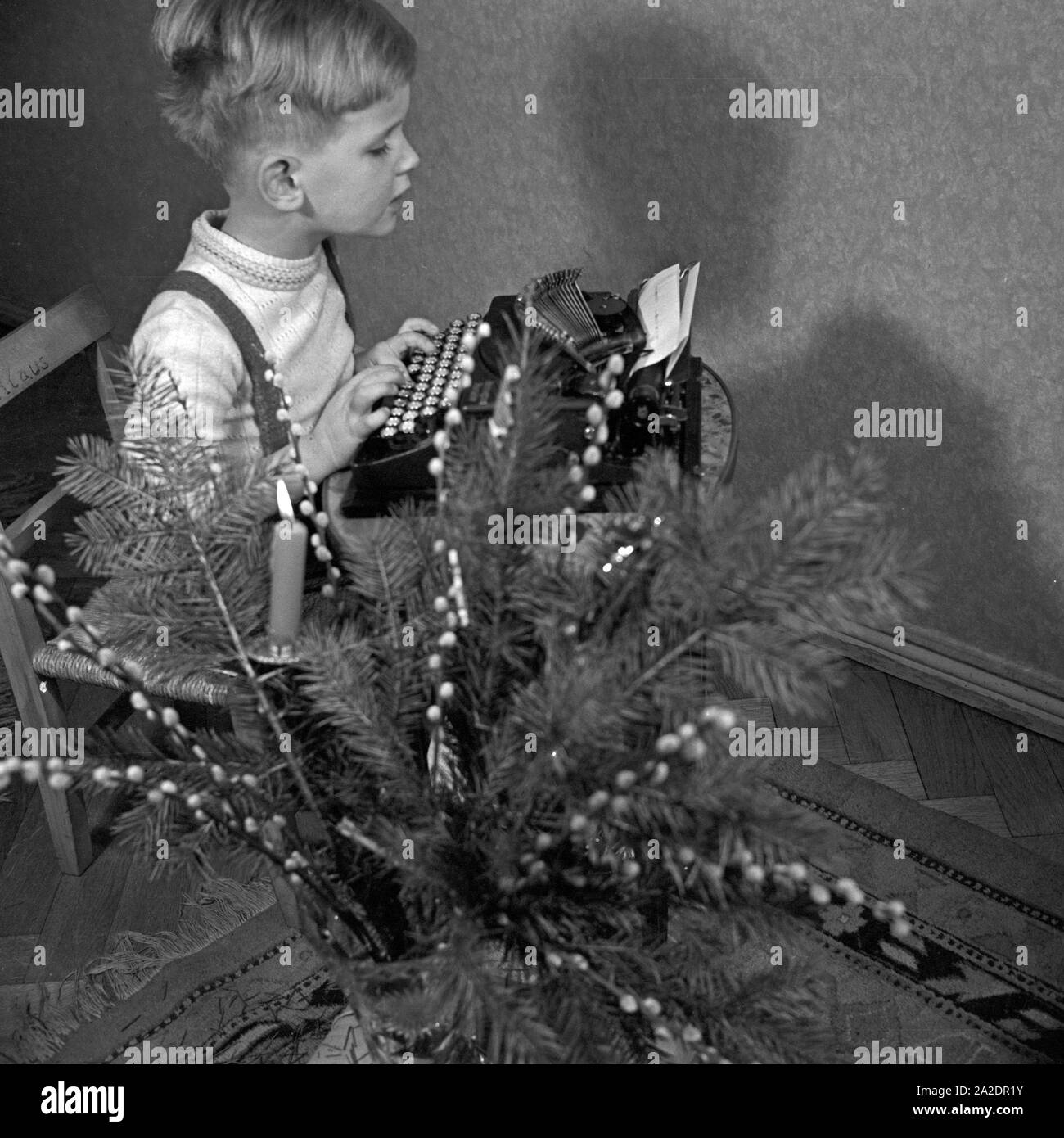 Ein kleiner Junge schreibt seinen Wunschzettel an den Weihnachtsmann mit der Schreibmaschine, Deutschland 1930 er Jahre. Un petit garçon tapant sa liste de souhaits de Noël - Allemagne 1930. Banque D'Images