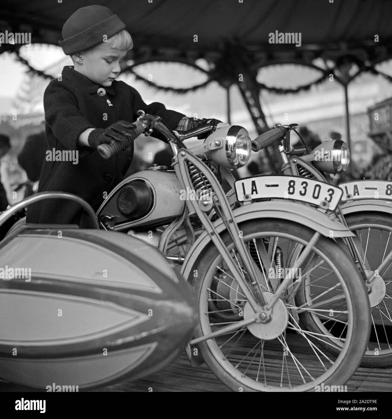 Ein kleiner Junge auf dem Motorrad und auf dem Kinderkarussels Weihnachtsmarkt Deutschland, 1930er Jahre. Un petit garçon sur la moto d'un carrousel kiddy au marché de noël, Allemagne 1930. Banque D'Images