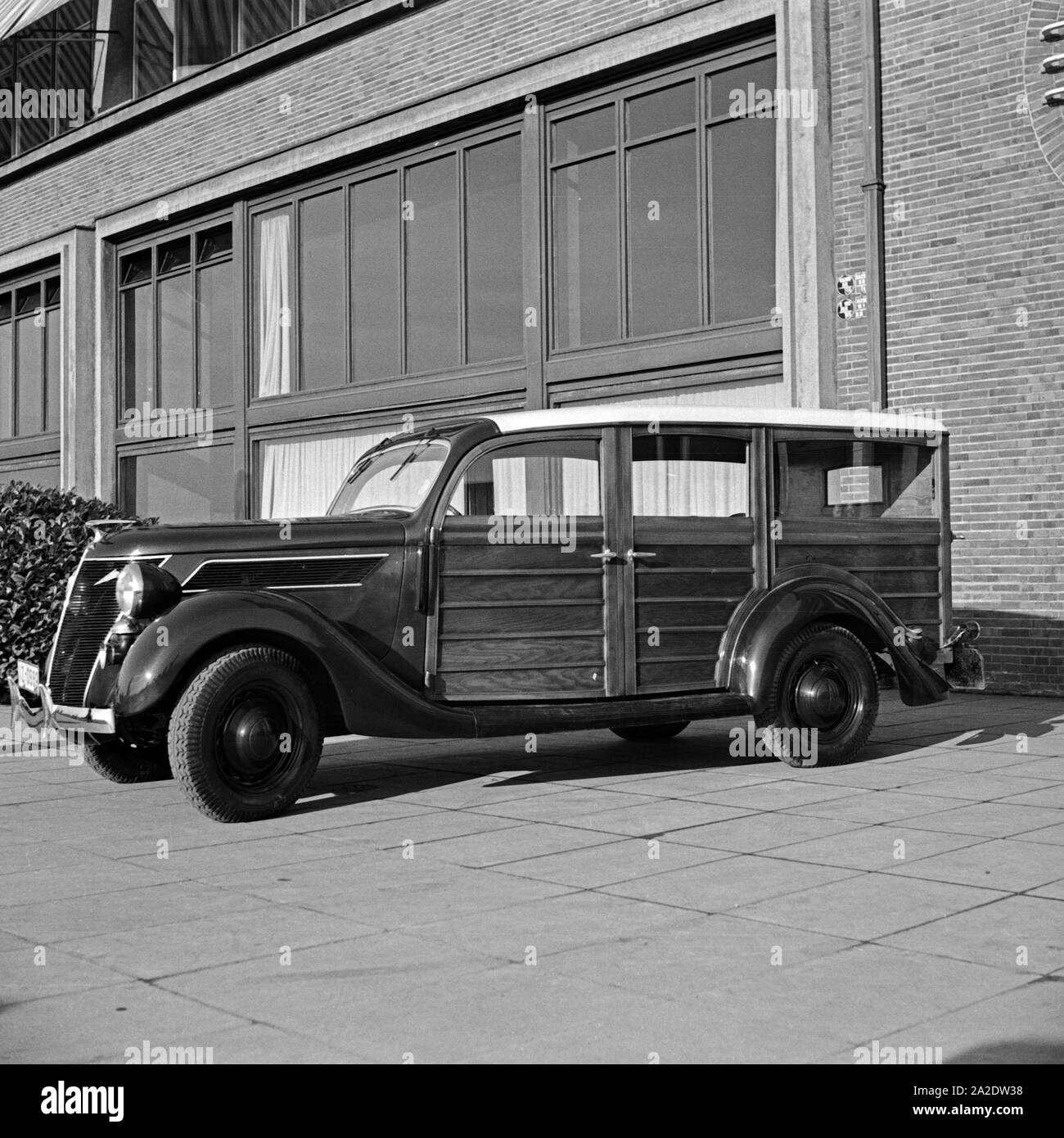 Ford V8 Ein Modell 68 Holzverkeidung Firmenzentrale mit der vor der Ford Werke in Köln Niehl, Deutschland 1930 er Jahre. Une Ford V8 modèle 68 van avec des feuilles de bois en face de l'administration centrale Ford allemand à Cologne, Allemagne 1930. Banque D'Images