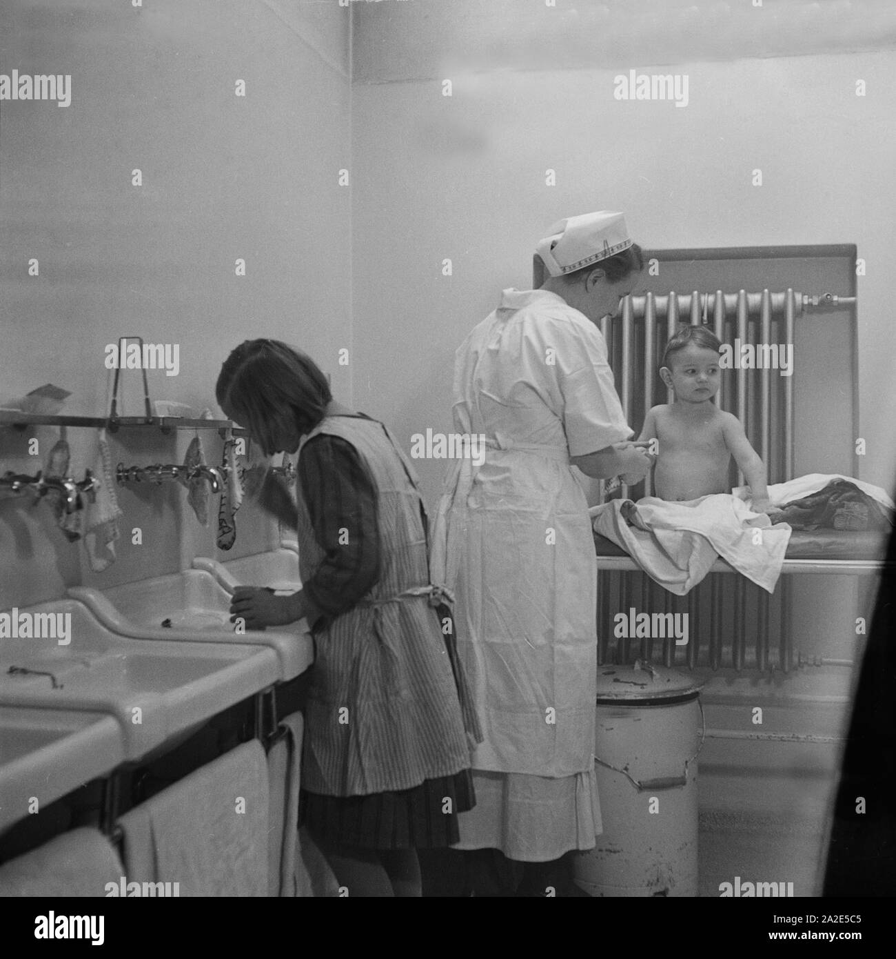 Eine Die Krankenschwester hilft beim Waschen im Mütterheim Dresden auf Schloß Dittersbach, Deutschland 1930 er Jahre. Une infirmière aide les enfants à laver le reste pour les mamans à Dittersbach château près de Dresde, Allemagne 1930. Banque D'Images
