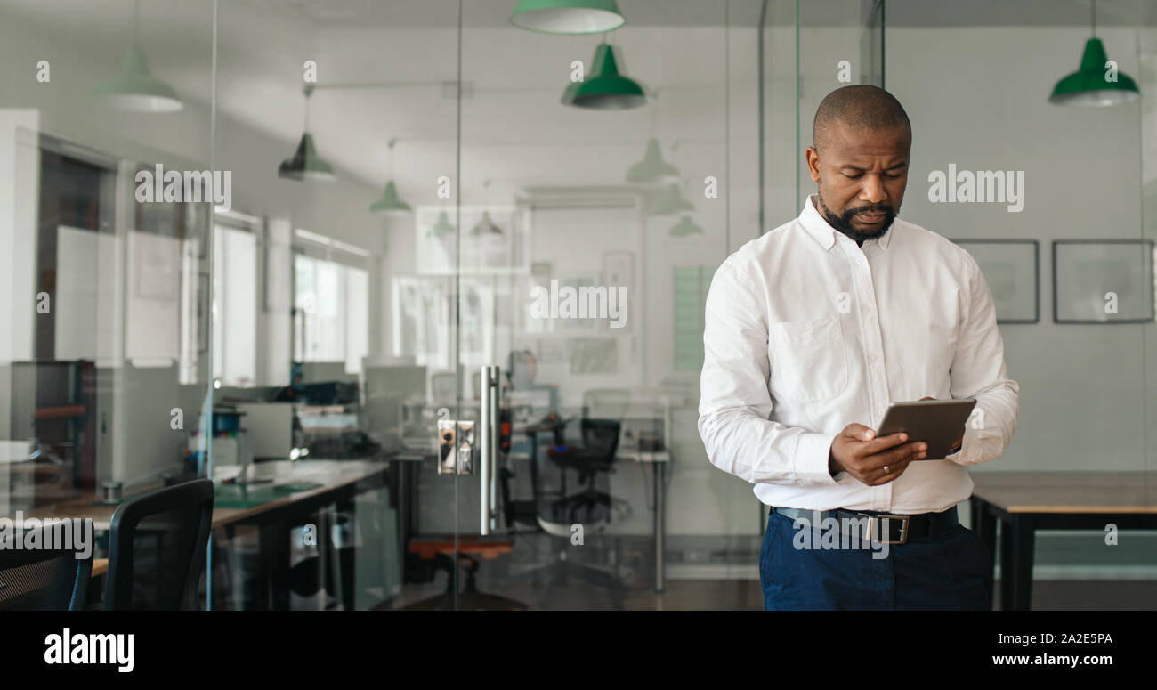 Young African American businessman à l'aide d'une tablette dans un bureau Banque D'Images