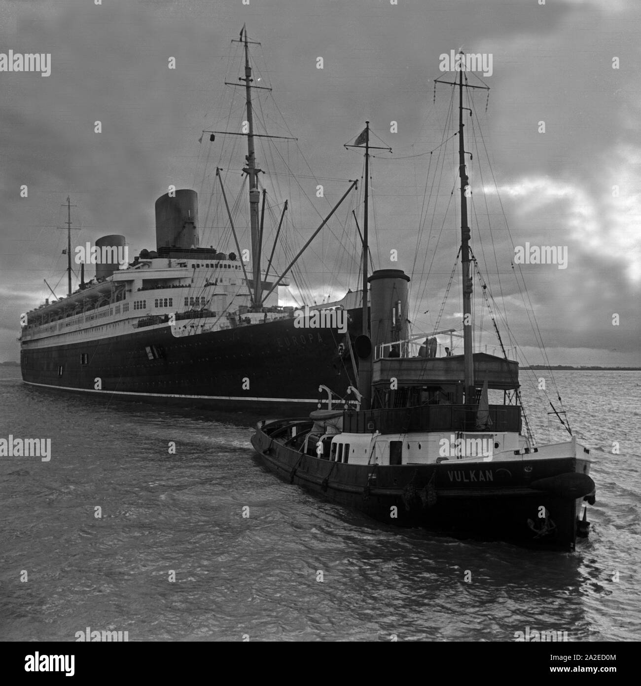 Der Schlepper 'Vulkan' zieht das Passagierschiff 'Europa' dans den Hafen von Berlin, Deutschland, 1930 er Jahre. Tug boat 'Vulkan' tirant paquebot 'Europa' dans le port de Bremerhaven, Allemagne 1930. Banque D'Images