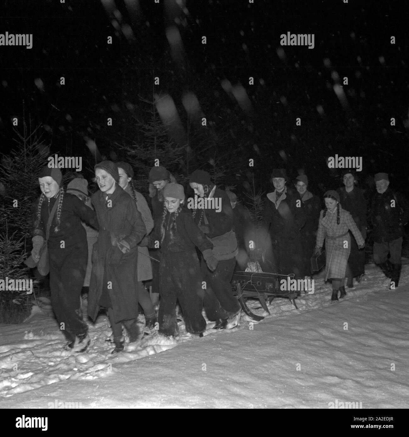 Eine Gruppe von Mädchen zieht nachts durch den verschneiten Wald, Deutschland 1930 er Jahre. Une bande de filles marcning à travers la forêt enneigée, Allemagne 1930. Banque D'Images