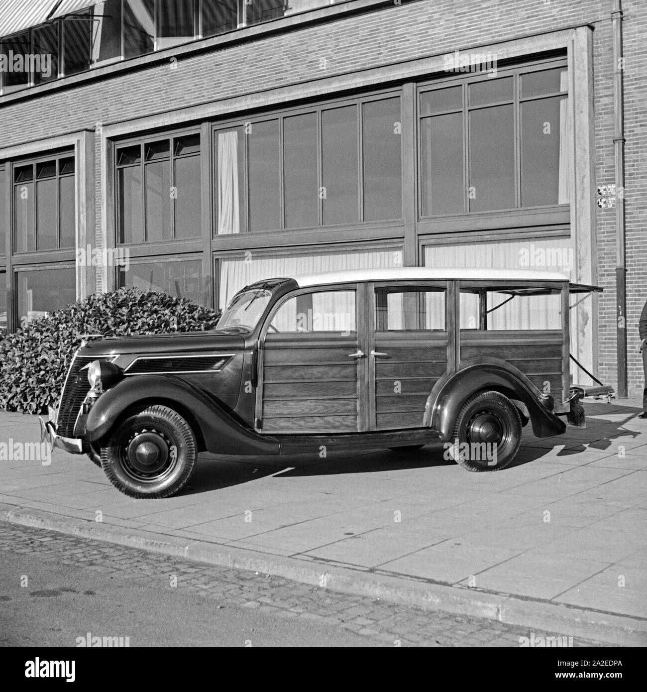 Ford V8 Ein Modell 68 Holzverkeidung Firmenzentrale mit der vor der Ford Werke in Köln Niehl, Deutschland 1930 er Jahre. Une Ford V8 modèle 68 van avec des feuilles de bois en face de l'administration centrale Ford allemand à Cologne, Allemagne 1930. Banque D'Images