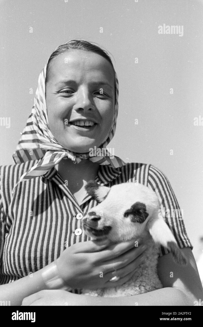 Eine junge Frau mit einem gescheckten Zicklein, St Märgen im Südschwarzwald, Deutschland 1930 er Jahre. Une jeune femme tenant une chèvre tachetée kid, St Märgen dans le sud de la Forêt-Noire, Allemagne 1930. Banque D'Images