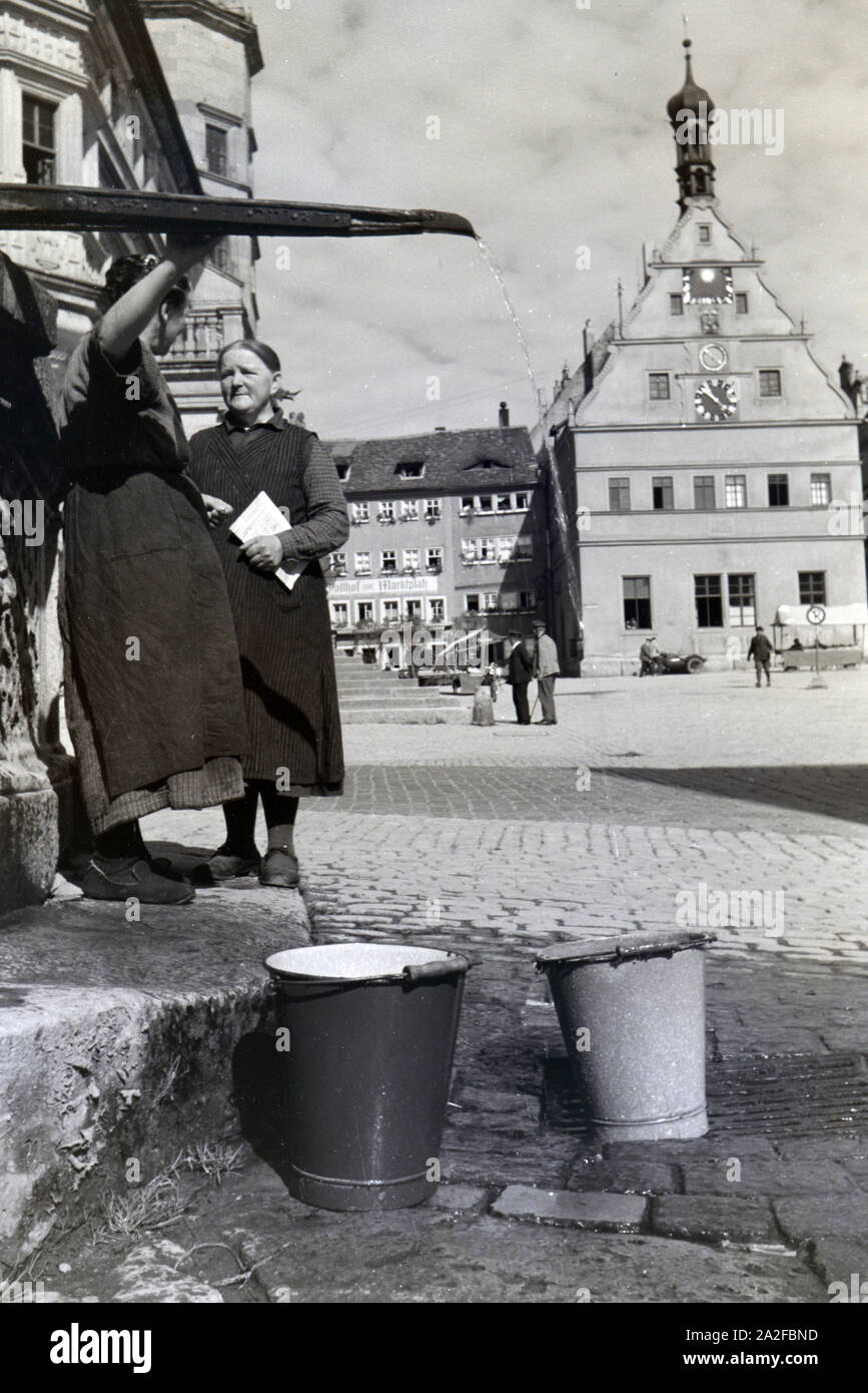 Zwei Frauen verwalten sich während Sie die Wassereimer mit Wasser aus dem Springbrunnen Am Marktplatz vor dem Rathaus und der Ratstrinkstube voll laufen lassen, Rothenburg ob der Tauber, Allemagne Allemagne Années 1930 er Jahre. Deux femmes ayant un chat tandis que le bucktes sont remplissage avec de l'eau de la fontaine sur la place du marché à proximité de la mairie et Ratstrinkstube à Rothenburg ob der Tauber, Allemagne 1930. Banque D'Images