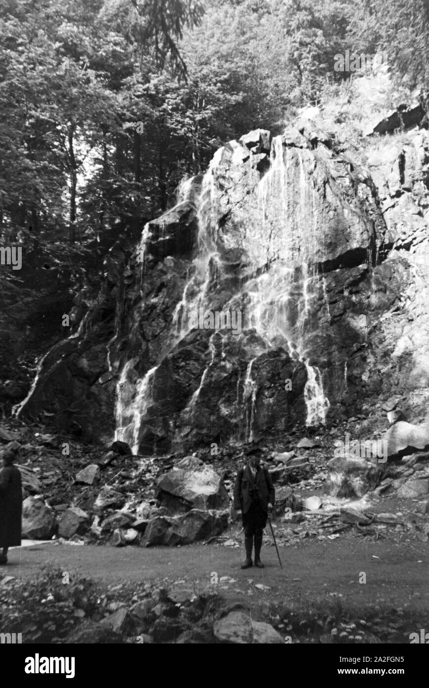 Ein Wanderer mit Wanderstock posiert vor dem Radauwasserfall à Bad Harzburg, Allemagne Allemagne Années 1930 er Jahre. Un randonneur avec un bâton de randonnée posant devant le Graben 15 Cascade à Bad Harzburg, Allemagne 1930. Banque D'Images